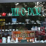 A tea shop window adorned with elegant signage vinyl decor, showcasing tea varieties, specials, or inviting imagery, creating an inviting and charming atmosphere to passersby.