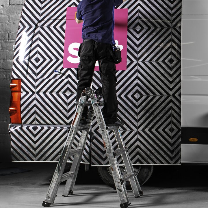 man standing on ladder wrapping van